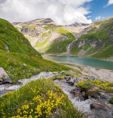 Standortmarketing_Michael Stabentheiner_Grossglockner (3)-original Bergsee in einer alpinen Landschaft zwischen grünen Berghängen.