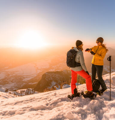 21_Kärnten Werbung GmbH_Rossmann Zwei Personen mit Schneeschuhen auf einem verschneiten Berggipfel bei Sonnenuntergang