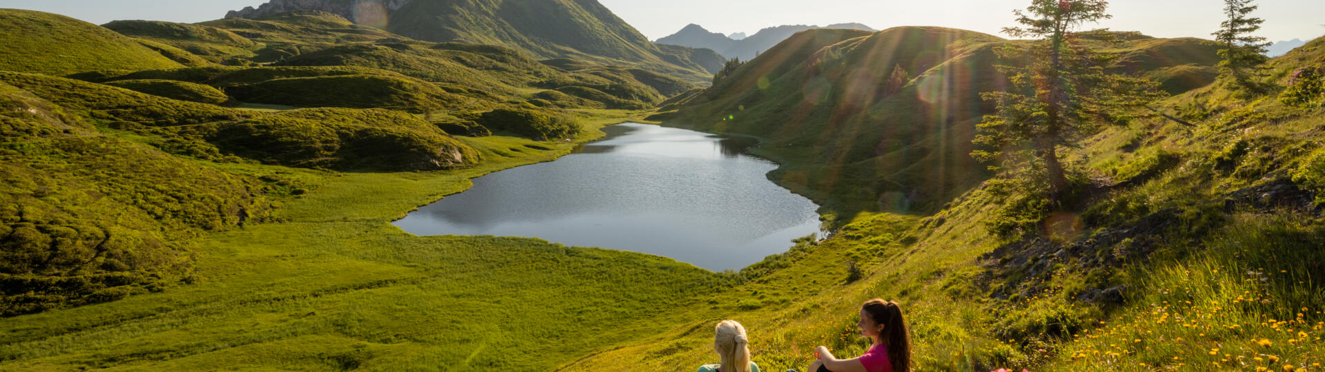 Bergsee in alpiner Landschaft mit zwei Personen am Ufer
