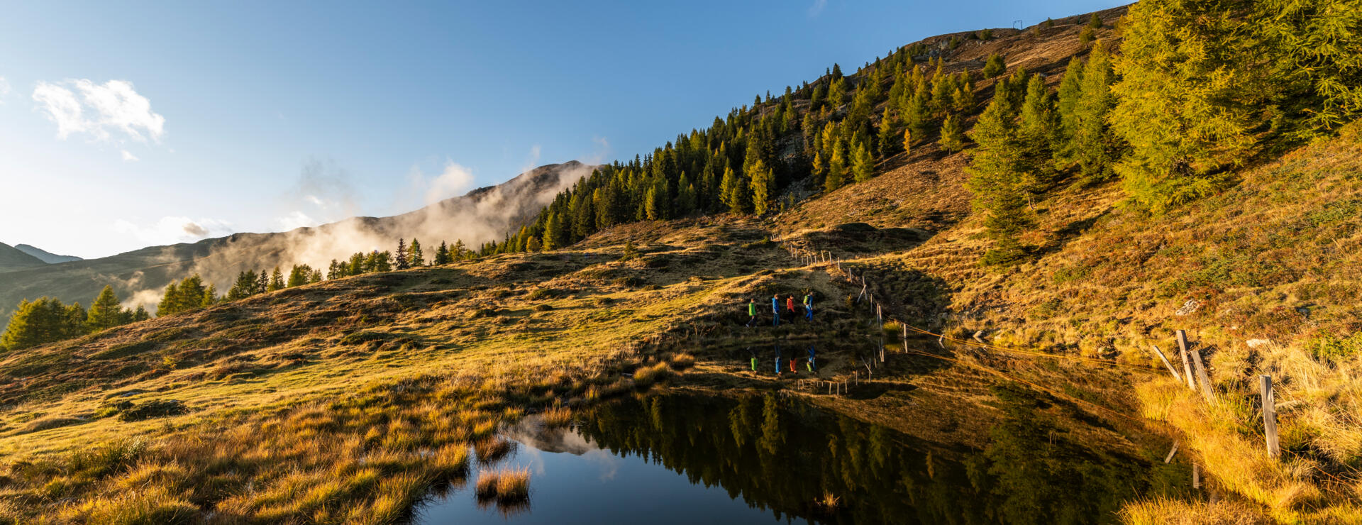Wandergruppe an einem Bergsee in herbstlicher Alpenlandschaft 
